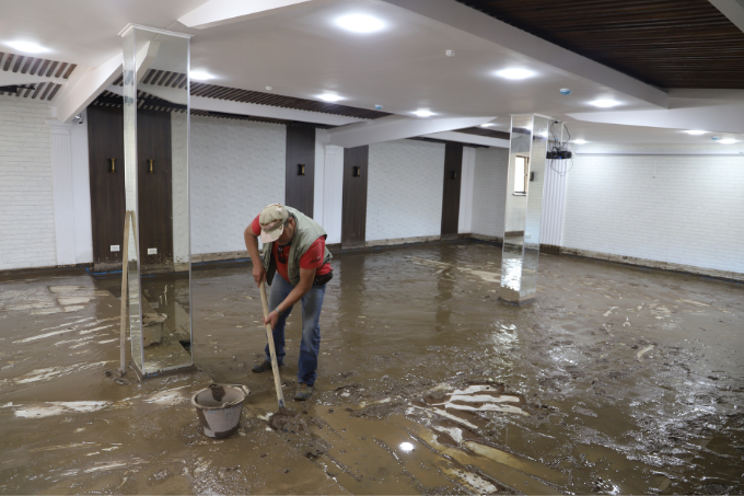 Mitarbeiter Tolkunbek Asykulov des neuen NABU-Rehazentrums in Kirgisistan räumt mit einer Schaufel Schlamm nach dem Schlammlawinenunglück aus dem Gebäude